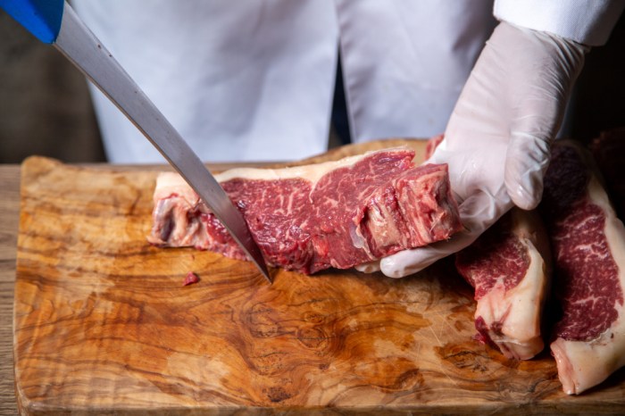 front-view-butcher-cutting-meat-white-gloves-holding-big-knife-wooden-desk
